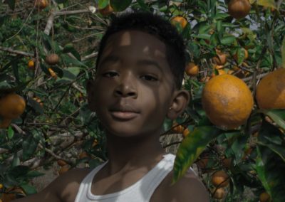 Jeremiah stands in an orange tree.