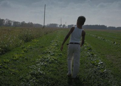 Jeremiah walks down a row in a field.